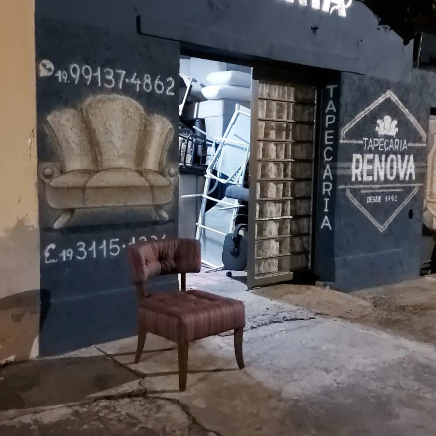 Fachada da oficina da Tapeçaria Renova com cadeira reformada na calçada
